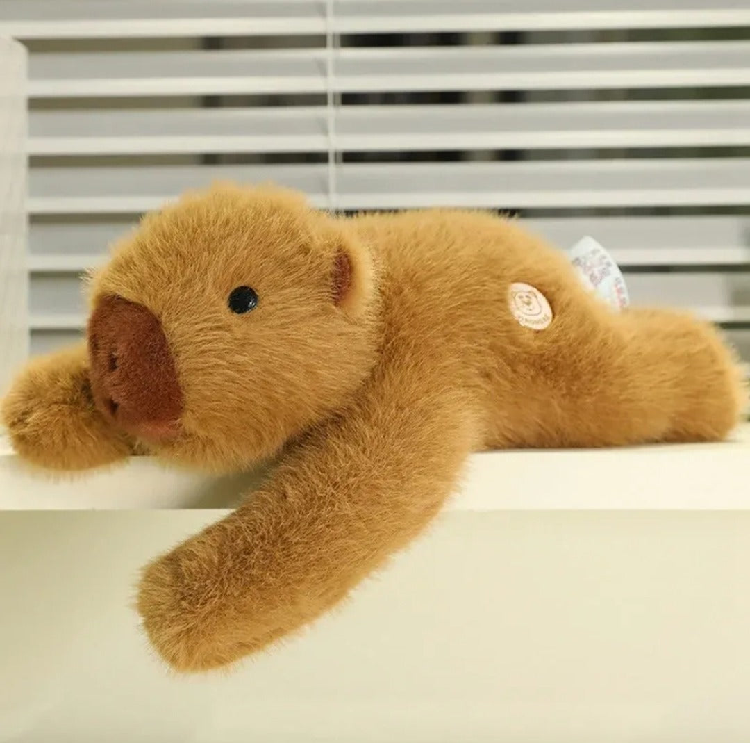 Weighted capybara plush lying on a white ledge with one arm hanging over